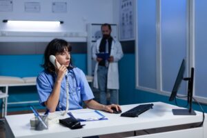 Woman nurse in uniform using landline phone for conversation