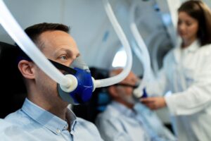 Mid adult man breathing through mask during hyperbaric oxygen therapy at clinic