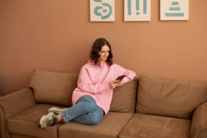 a girl sitting on a couch and using her phone